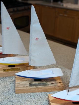 Blue-hulled sailboat award with engraved brass nameplate on the base