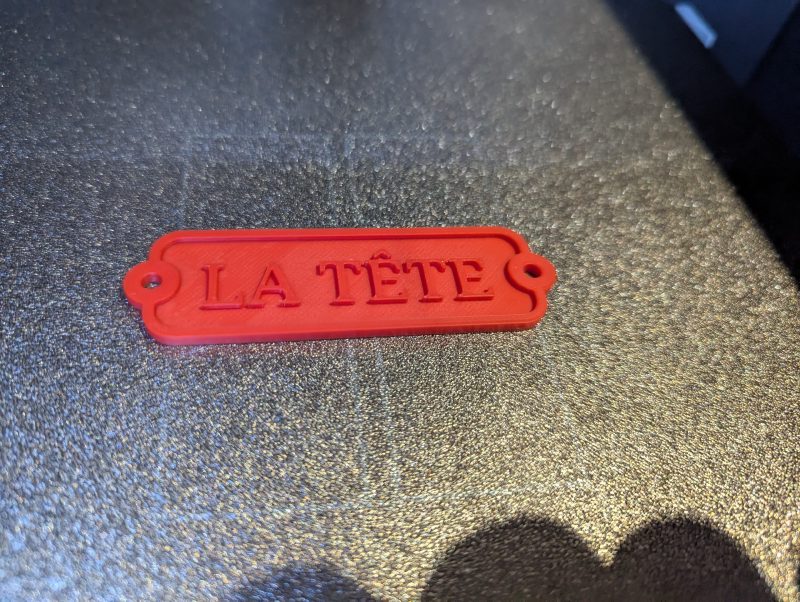 Custom red 3D printed nameplate with raised lettering reading La Tete