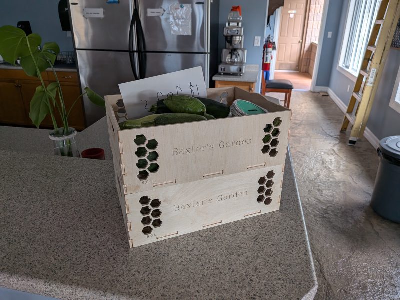Two produce boxes stacked on a kitchen counter, filled with zucchini