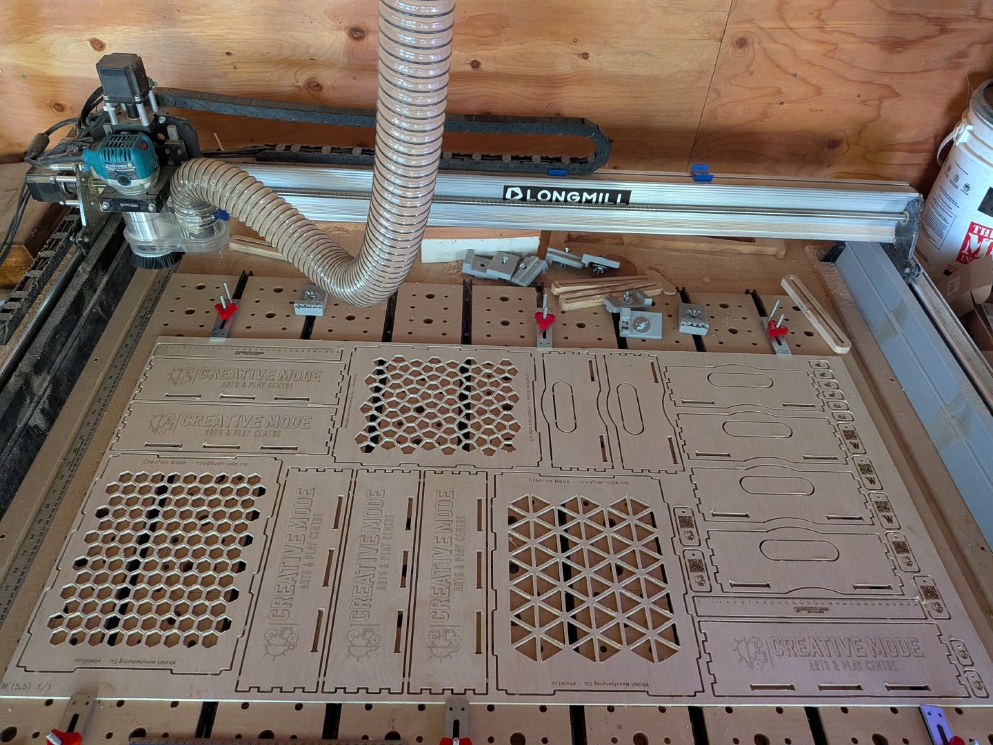 A quarter sheet of birch plywood on the CNC, nested with parts for three boxes, two rulers, keytags and zipper pulls