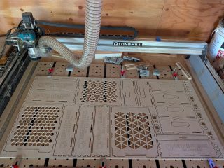 A quarter sheet of birch plywood on the CNC, nested with parts for three boxes, two rulers, keytags and zipper pulls