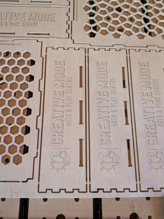 Close-up of box end panels engraved with the Creative Mode logo, next to a honeycomb panel