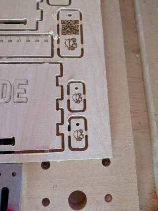 Corner of the cut sheet with engraved Creative Mode tags and the finger-joint edge of a side panel