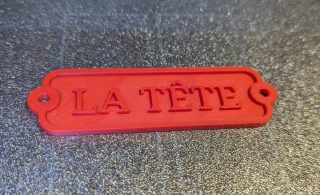 3D printed door label mounted in place, showing the raised lettering